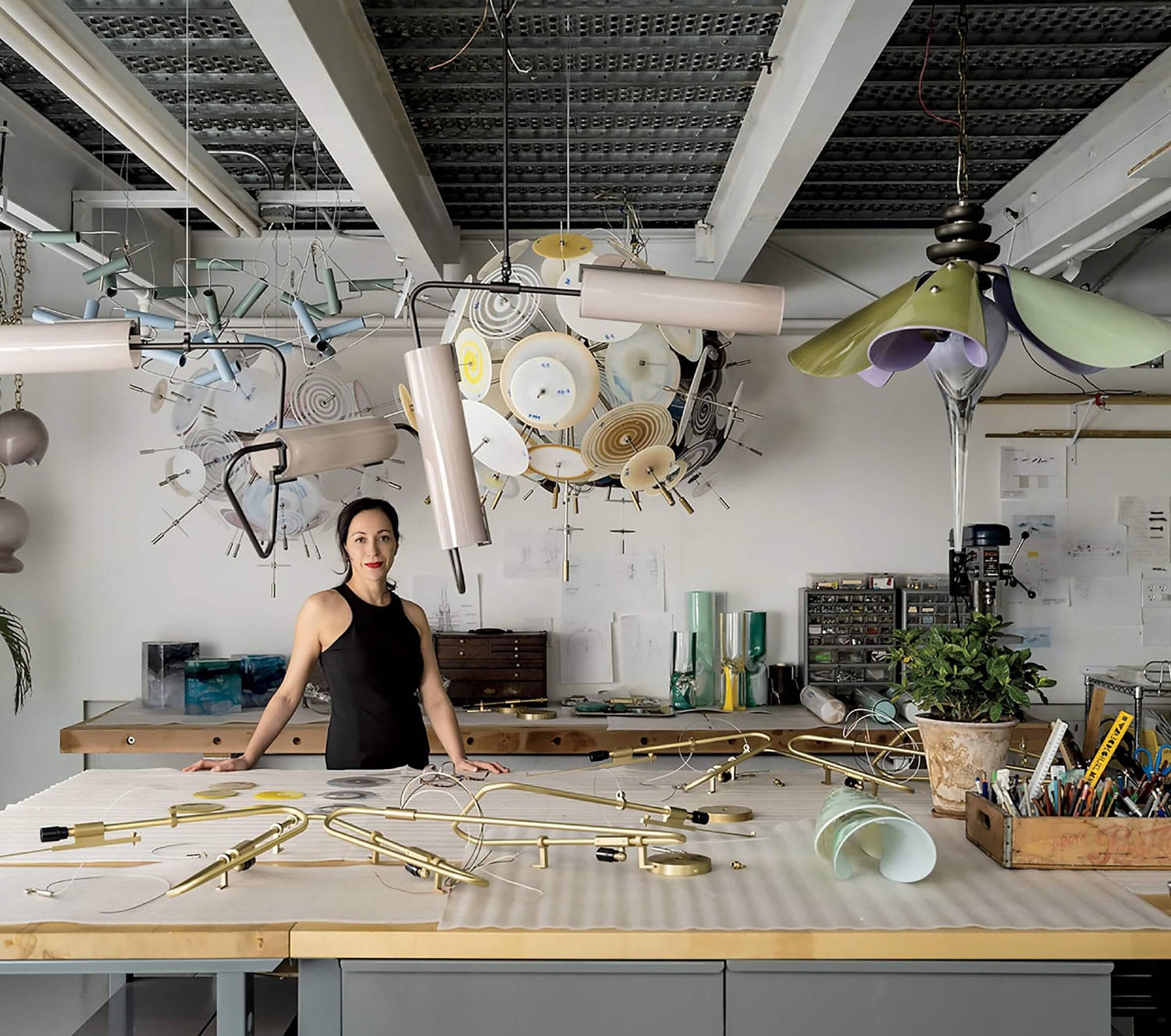 A woman sitting at a desk with lots of objects.