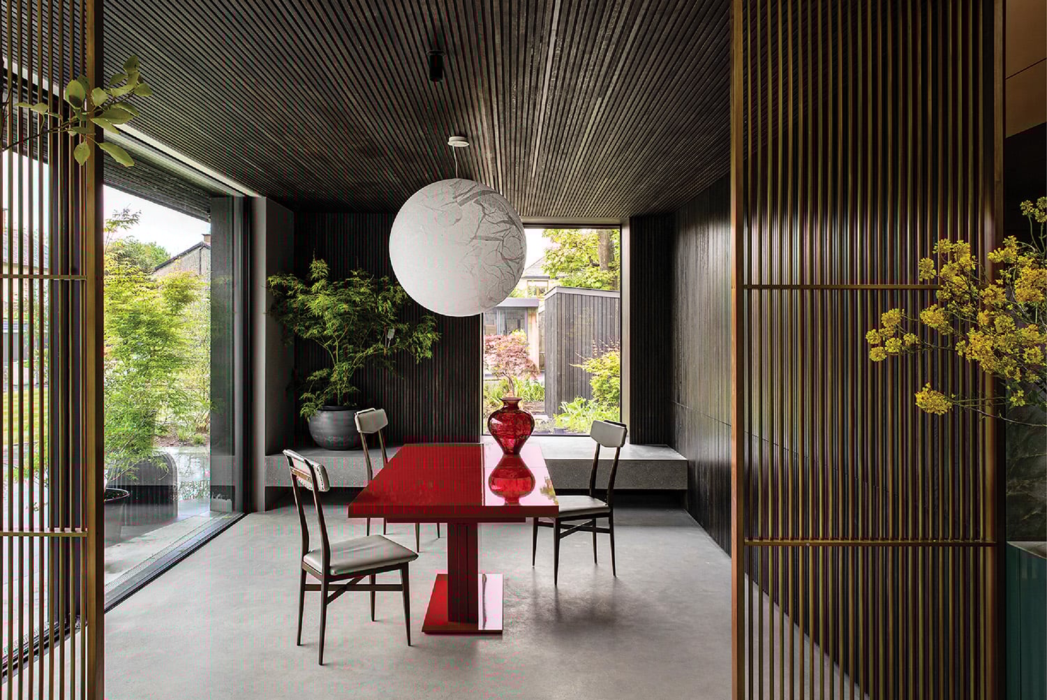 A dining room with a red table and chairs.