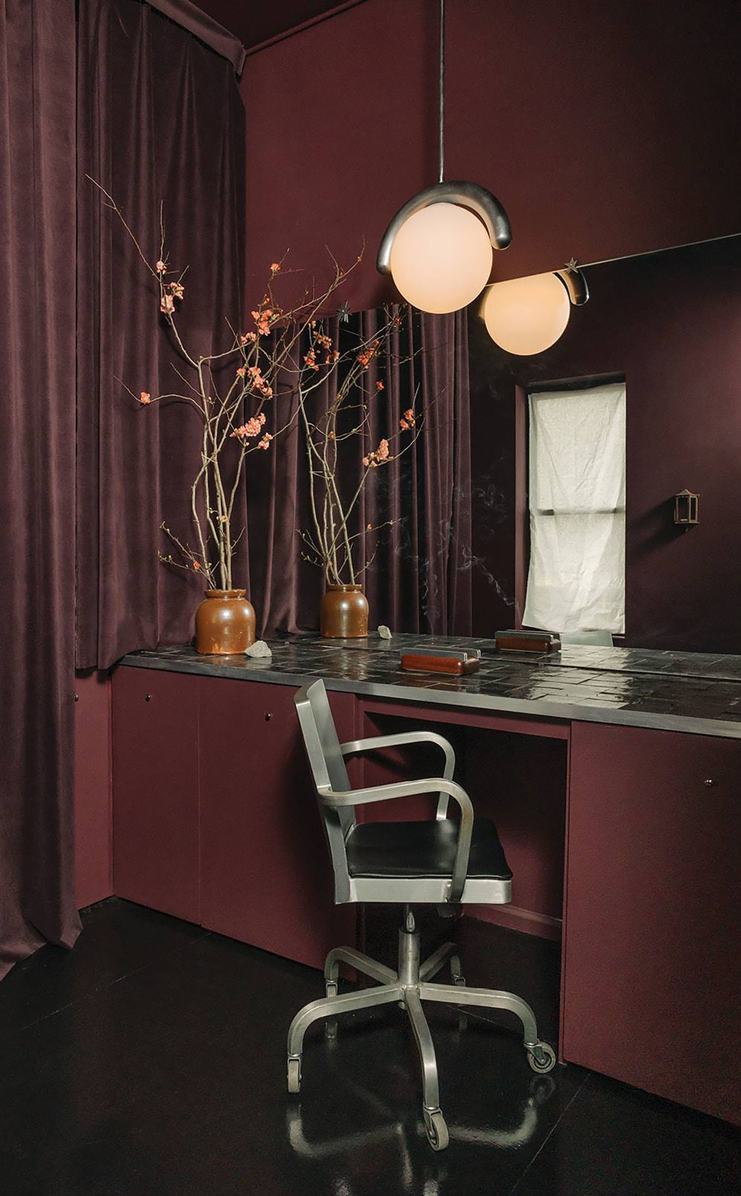 A desk with a chair and a vase of flowers.