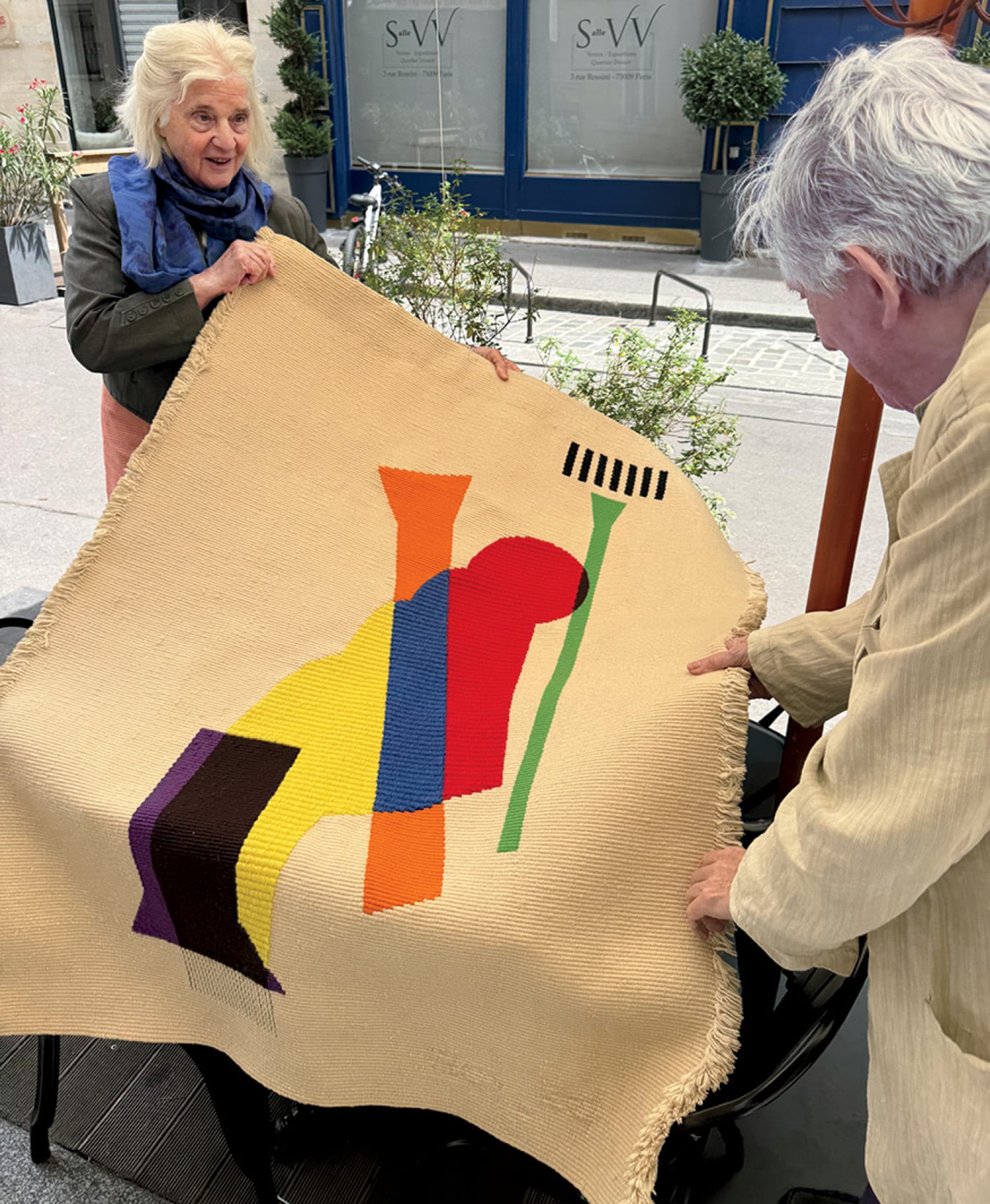 A man and woman holding a large piece of art.