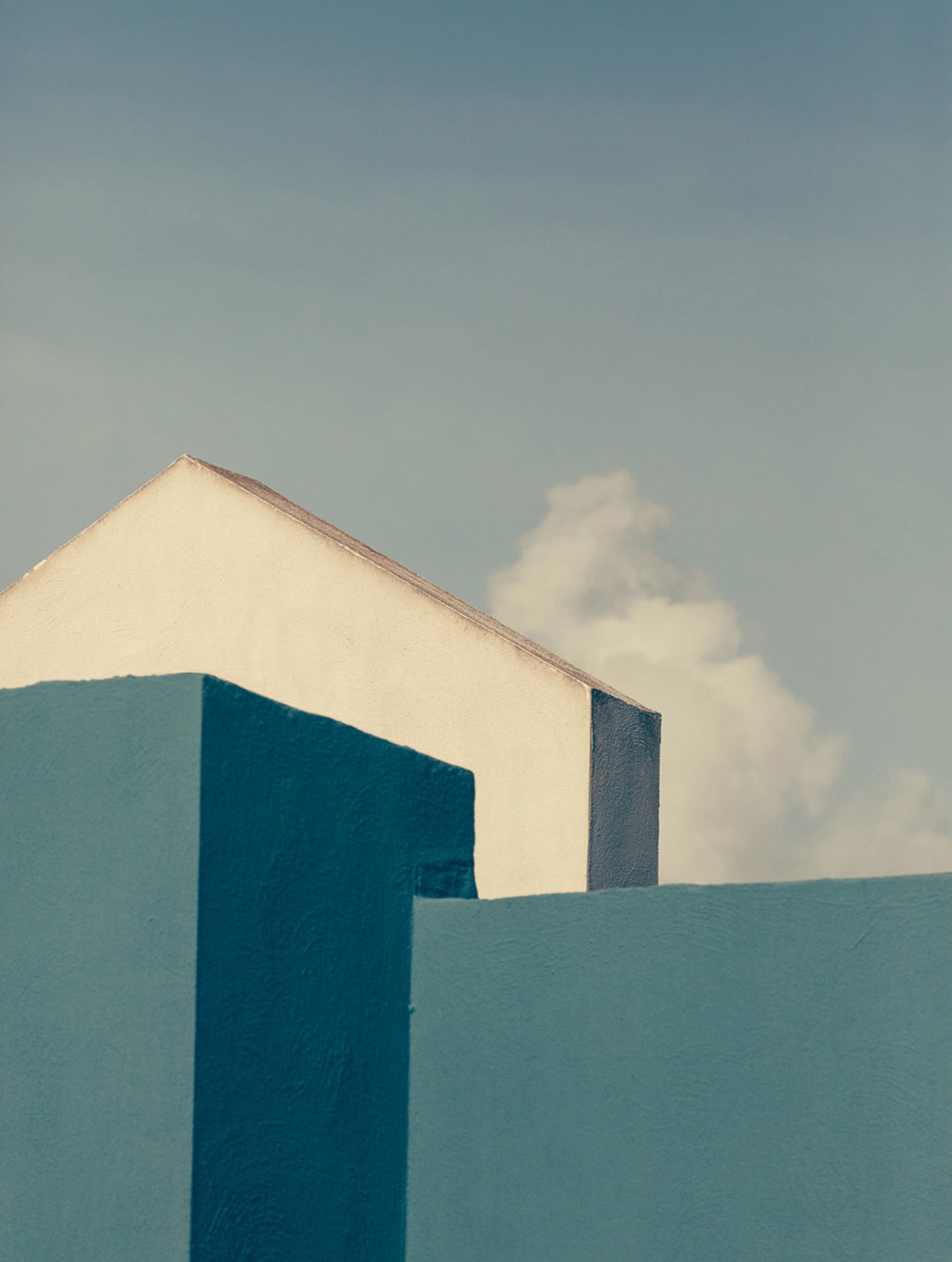 a blue wall with a white building in the background