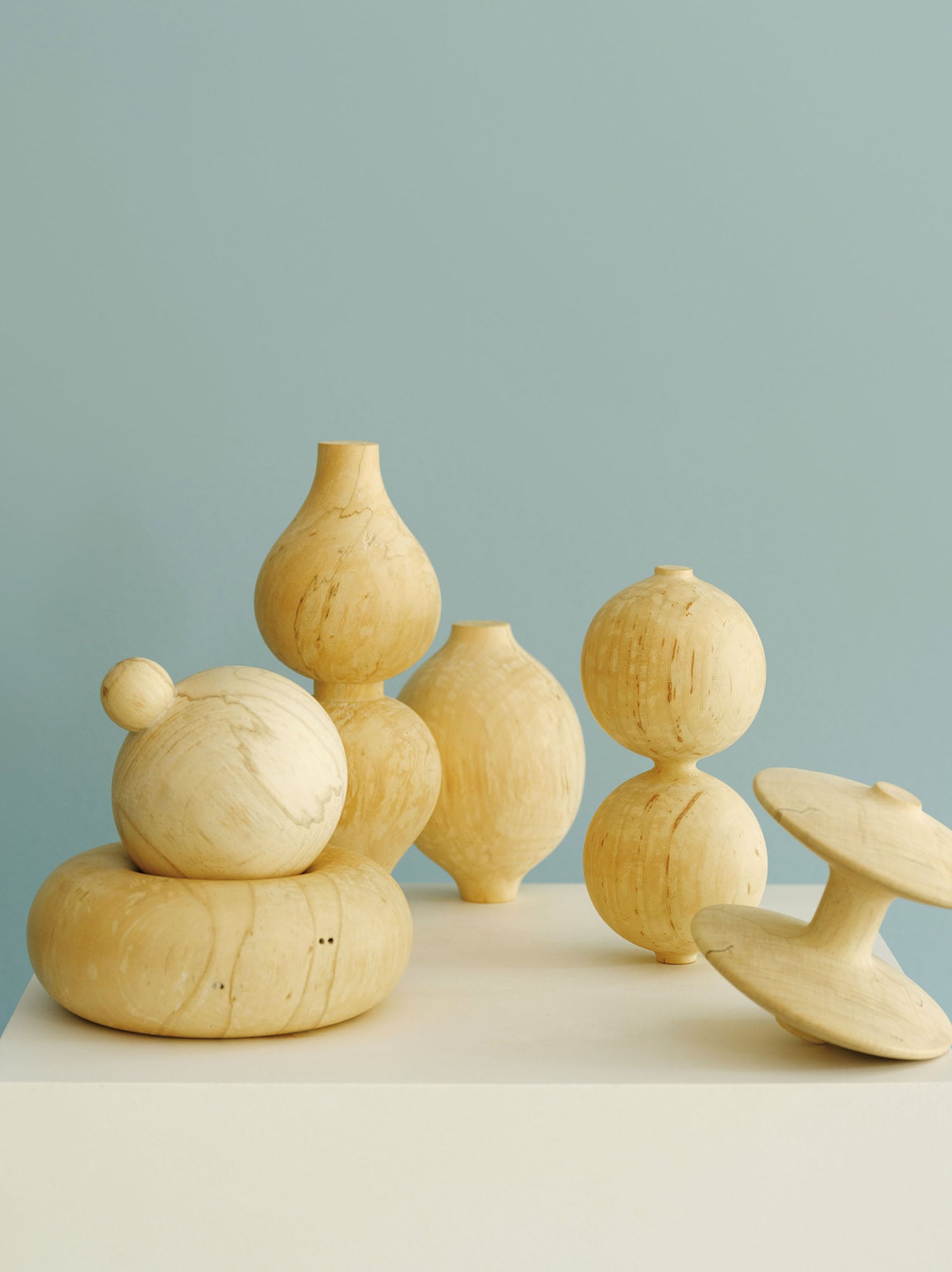 A group of wooden birds sitting on a white surface.