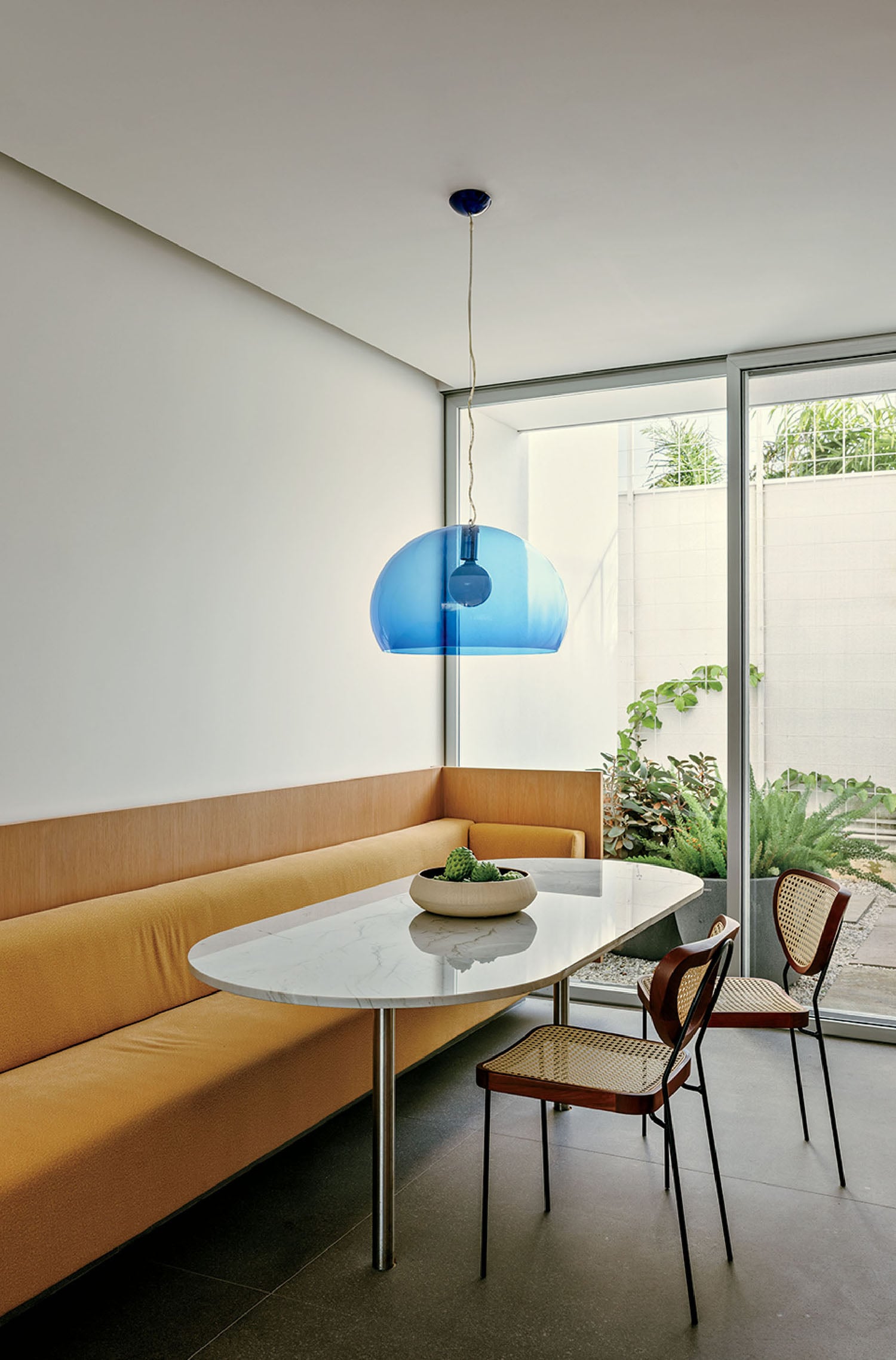 A table and chairs in a room with a window.
