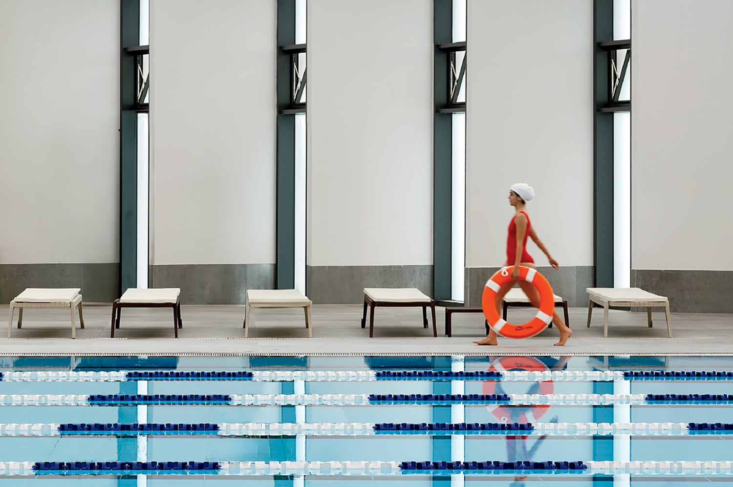 A woman in a red swim suit is sitting on the edge of a swimming.