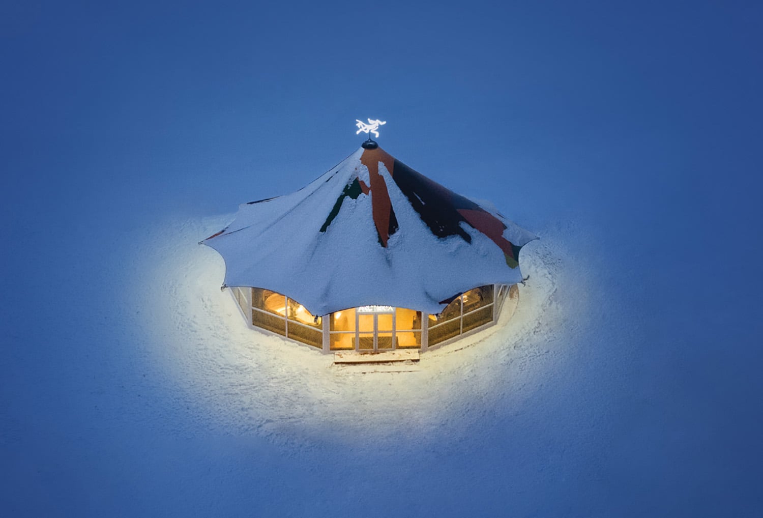 A small house in the snow with a light on top.