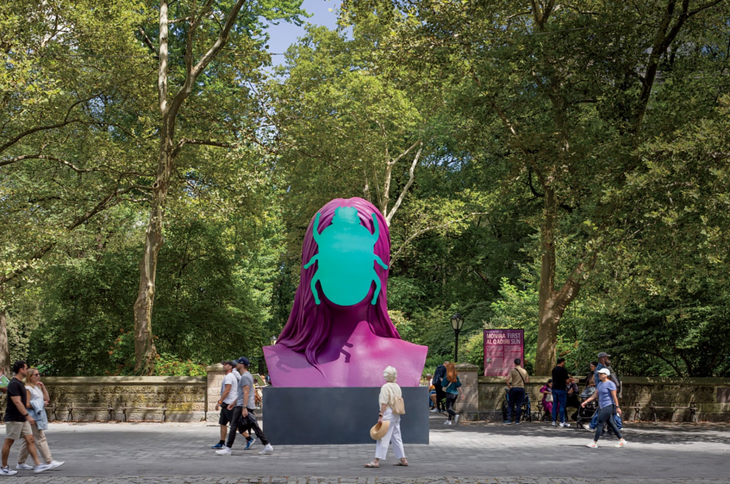 A large sculpture in a park with people walking around.