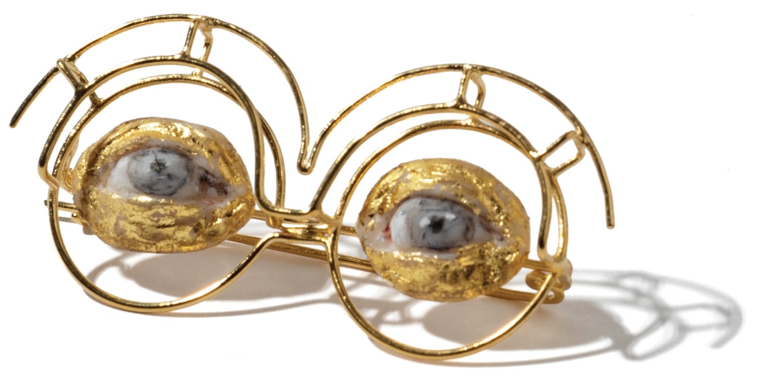 A pair of gold earrings with a white pearl.