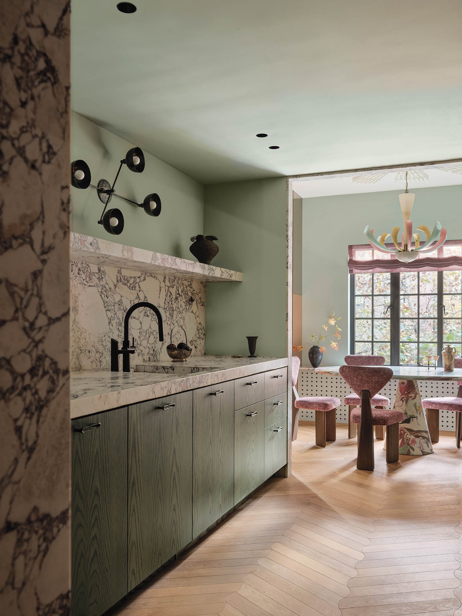 sage green kitchen space with marble backsplash and black fixtures