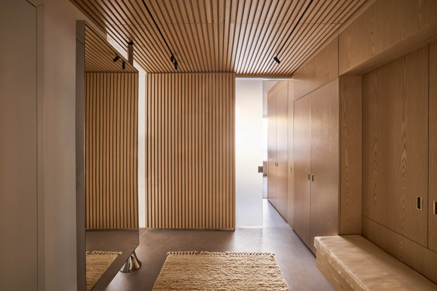 formal entryway of apartment with neutral rug and bench